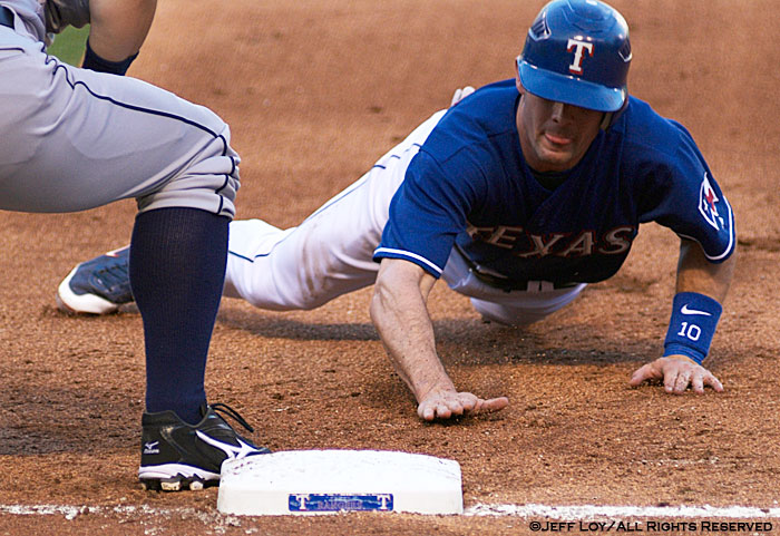Texas Rangers third baseman Michael Young dives back to first base to avoid being picked off.
